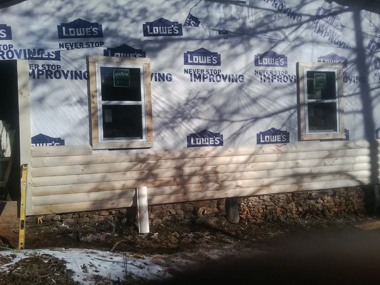 House wrap and new log siding going up on an exterior wall in Bath
